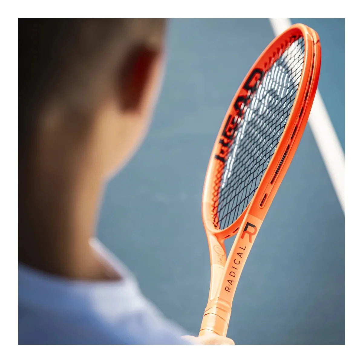 Junior tennis player holding a Head Radical racket, orange